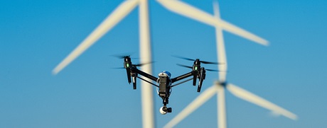 A drone flying in between wind turbines